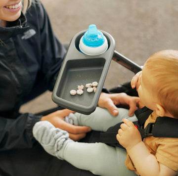 Mom with a baby in the Roam stroller with the Roam Snack & Drink Tray attached